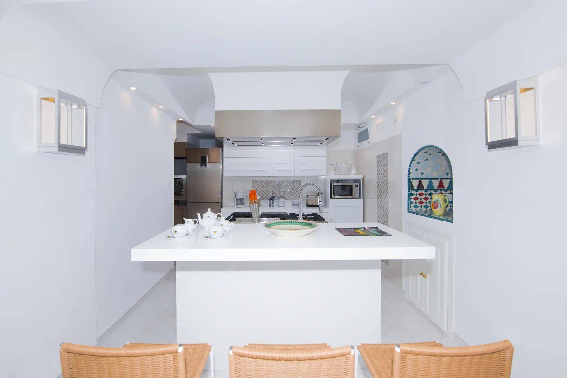 Cucina moderna e luminosa con isola centrale e decorazioni geometriche colorate.