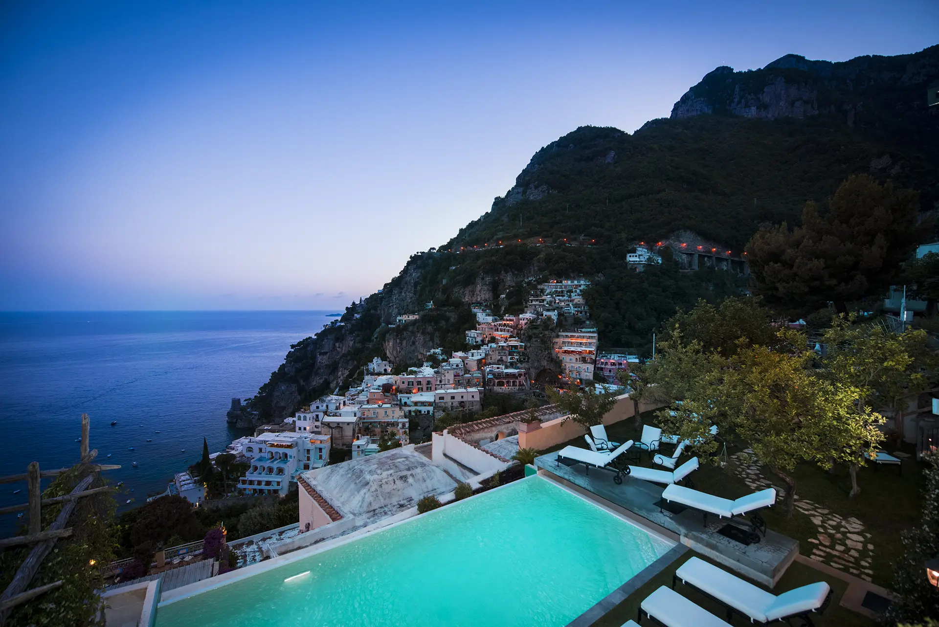 Vista serale di Positano con piscina in primo piano e il mare sullo sfondo.