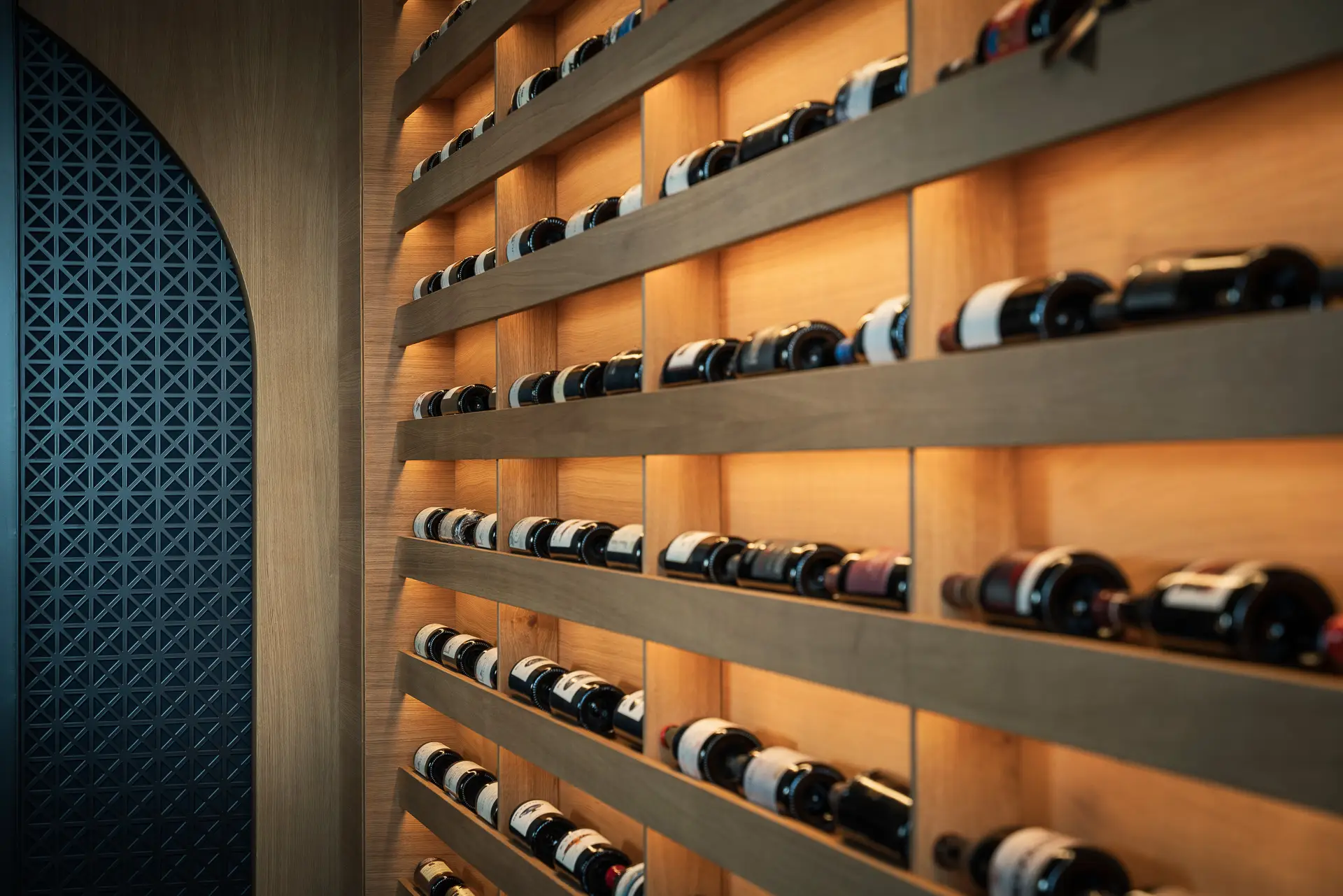 Scaffale illuminato con bottiglie di vino disposte orizzontalmente.