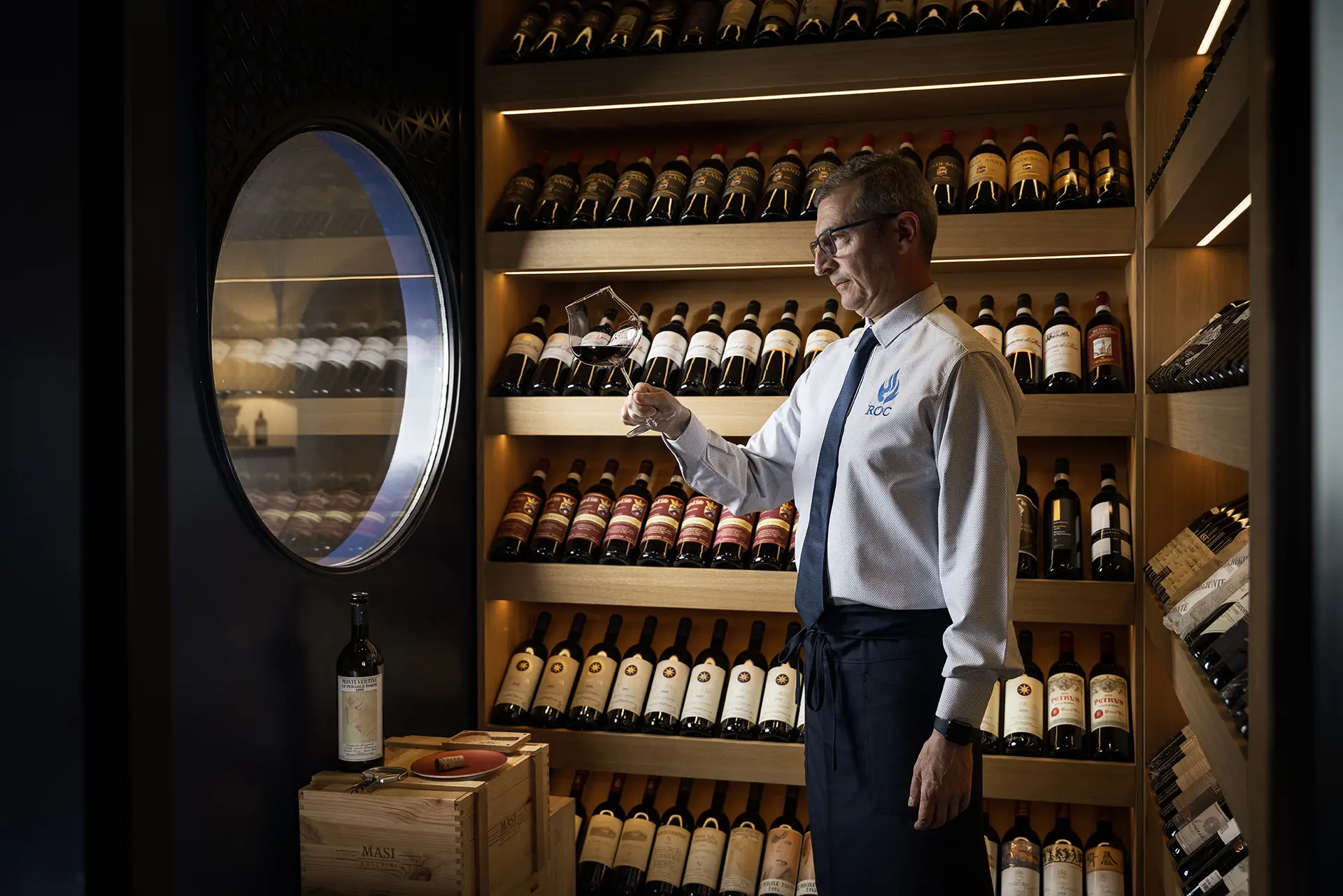 Sommelier in cantina mentre valuta un bicchiere di vino.
