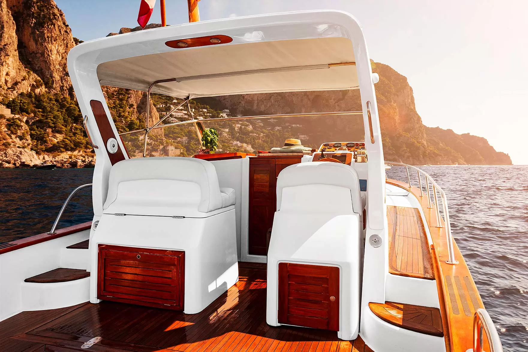 Interno di uno yacht di lusso con vista su scogliere e mare al tramonto.