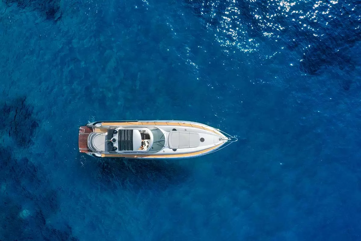 Uno yacht visto dall'alto naviga su un mare blu profondo.